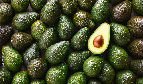Top view of whole ripe green and brown avocados placed together as background, half avocado in center