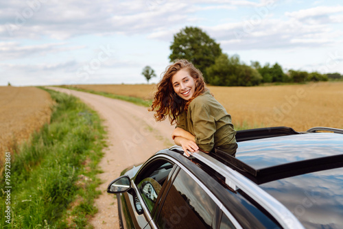 Happy woman on summer road trip travel vacation leaning out car window. Summer trip. Nature, transportation, active life.