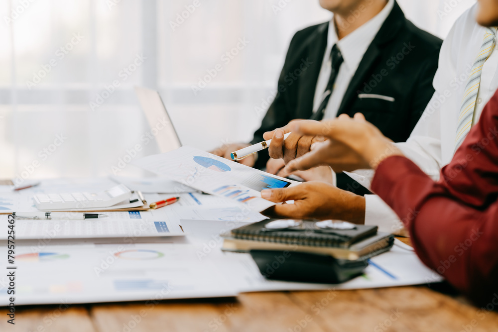 Two people are looking at a graph on a table. One of them is holding a pen. The graph shows a comparison of different data points Two people are looking at a graph on a table. One of them is holding a pen. The graph shows a comparison of different data points