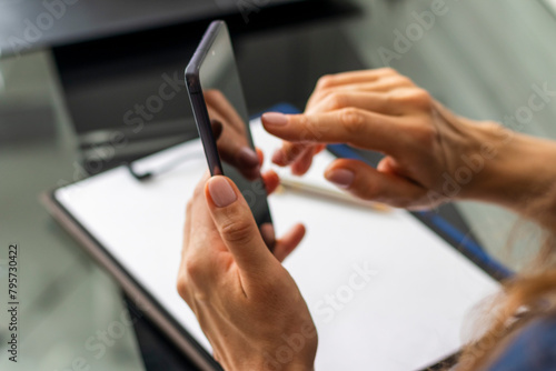 Close up shot of the woman with beautiful hands sitting in the meeting room during business meeting, using her phone. Business photo