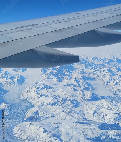 view from window of airplane flying over icy mountains