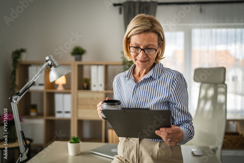 Mature woman watch tablet and drink coffee at office at work