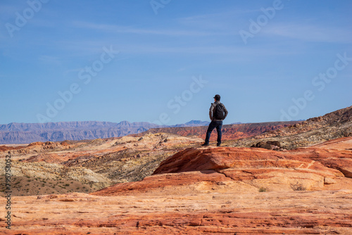 A man is standing and enjoying the spectacular view of Valley of Fire. It is one of geologic wonderland with 2000 year old petroglyphs carved into massive red sandstone formations in the Mohave Desert