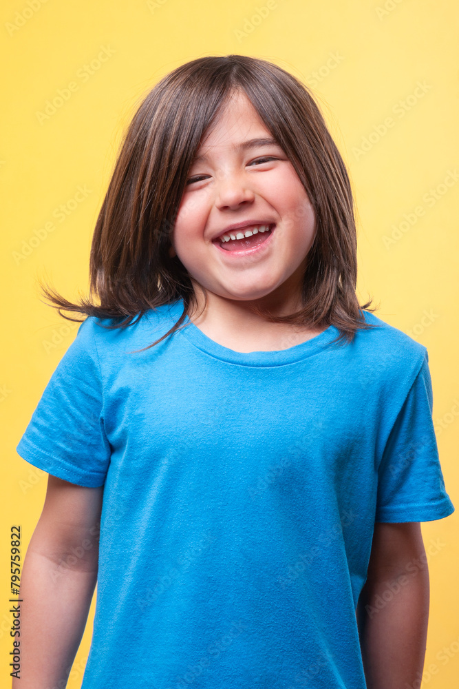 A young boy with brown hair is smiling and wearing a blue shirt A young boy with brown hair is smiling and wearing a blue shirt