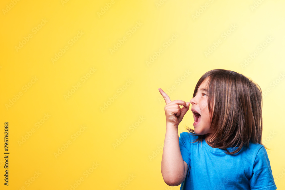 Boy with blue t-shirt and long brown hair points with his finger to the empty space in the image Boy with blue t-shirt and long brown hair points with his finger to the empty space in the image