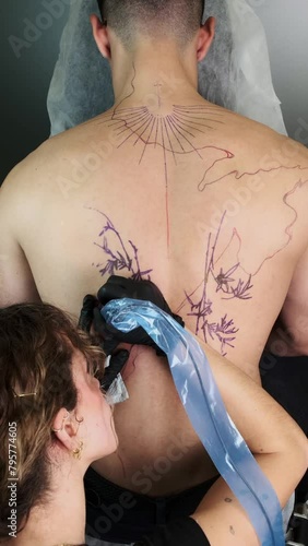 Tattoo artist inking a large backpiece design photo