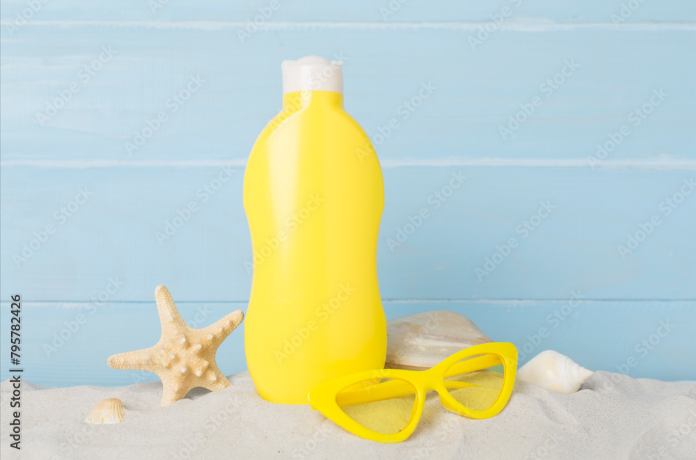 Sunscreen lotion with summer decor on sand against wooden background Sunscreen lotion with summer decor on sand against wooden background