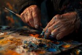 Close-up of artist's aged hands with a brush mixing oil paints on a vibrant palette