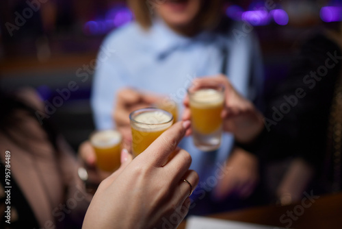 Group cheers with shot glasses of Paulaner hefeweizen wheat beer at fun event photo