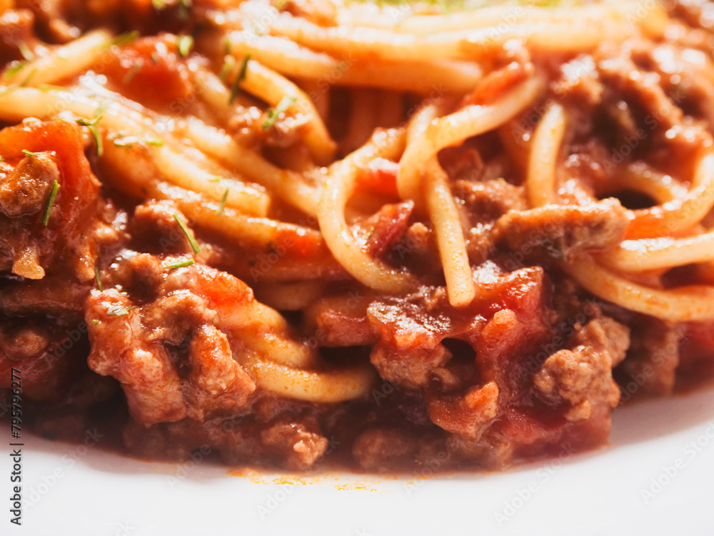 Spaghetti Bolognese serving on a white dish. Premium high quality meal with pasta, minced meat and tomato sauce. Top ingredients and herbs. Close up details shot. Light and airy look. Spaghetti Bolognese serving on a white dish. Premium high quality meal with pasta, minced meat and tomato sauce. Top ingredients and herbs. Close up details shot. Light and airy look.