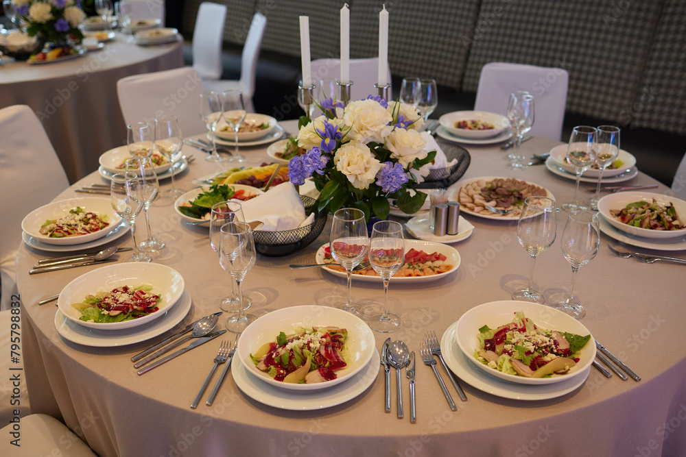 Table set with yellow tablecloth, plates of food, and wine glasses