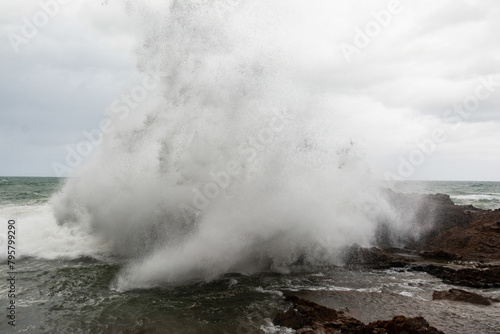 Immense waves hitting a large rock at the edge of the beach. Force of nature.