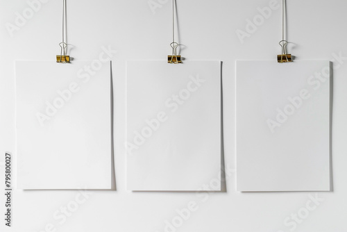 Blank paper frames suspended by clips against a pristine white backdrop -