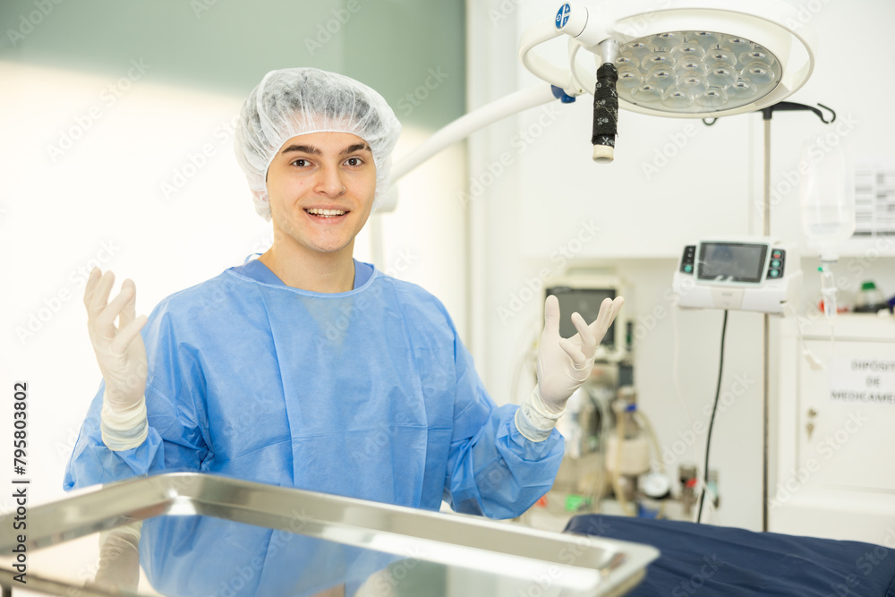 Man veterinarian in full surgical attire is standing in operating room ...