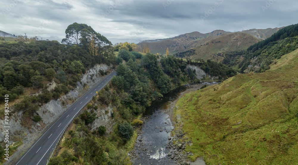 The Mangawhero River and rural road in the countryside. The trees are autumn yellow. Kakatahi, Whanganui, Manawatū-Whanganui, New Zealand.