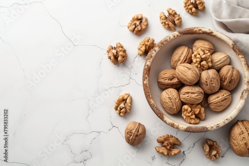 A bowl of walnuts is on a white background. The walnuts are scattered around the bowl, with some of them in the bowl and others on the table photo