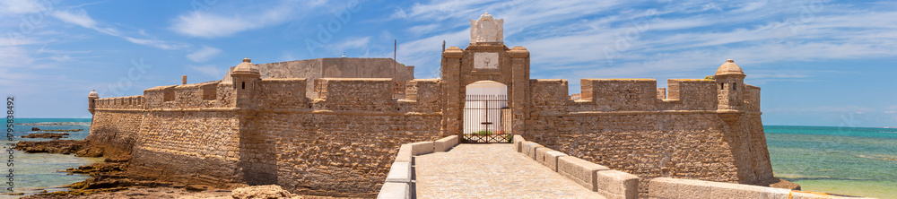 Obraz premium Fort San Sebastian and the stone breakwater bridge leading to it on a sunny day.