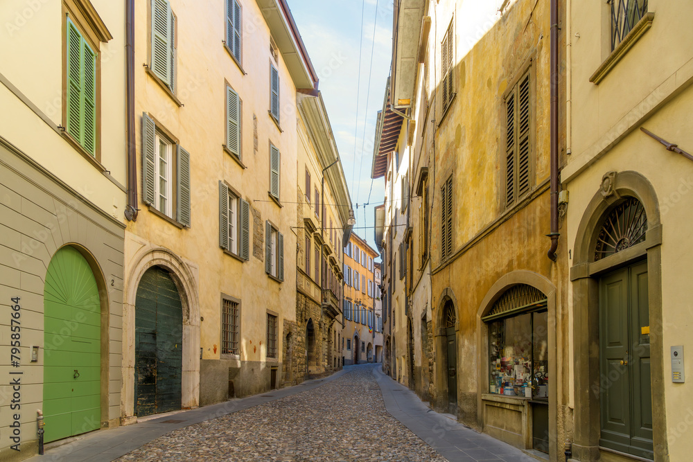 A picturesque narrow alley leading in the historic medieval old town walled Città Alta district, the historic upper district of the city of Bergamo, Italy, in the Lombardy region.	