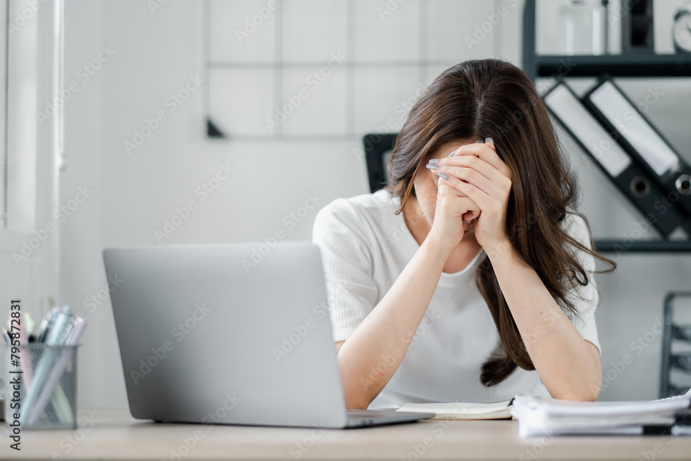 A woman is sitting at a desk with a laptop and a notebook A woman is sitting at a desk with a laptop and a notebook