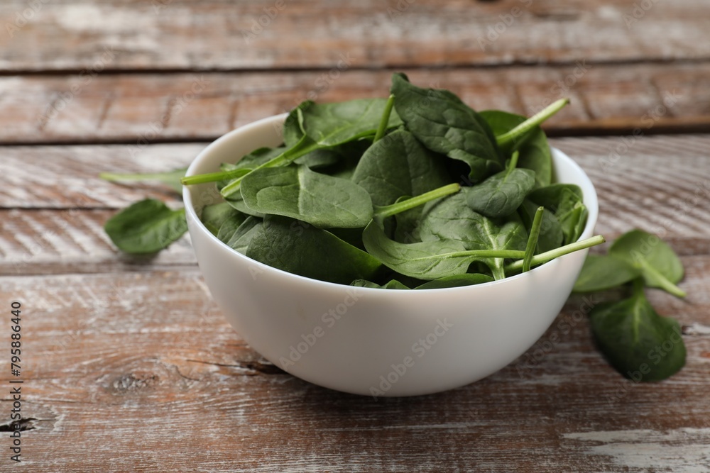 Fresh spinach leaves in bowl on wooden rustic table, closeup Fresh spinach leaves in bowl on wooden rustic table, closeup