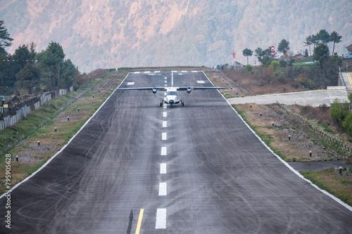 An aircraft landing on the runway in Lukla airport the most dangerous airport in the world in Nepal. The runway rests on a hillside in the town of Lukla, Nepal. photo