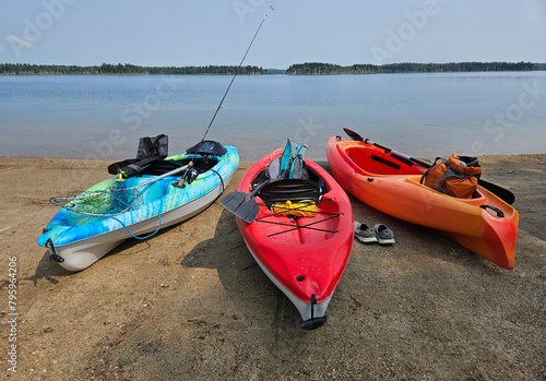 Fotografie Three colorful kayaks lying on the sandy beach along the shoreline of a freshwater lake prior to launching