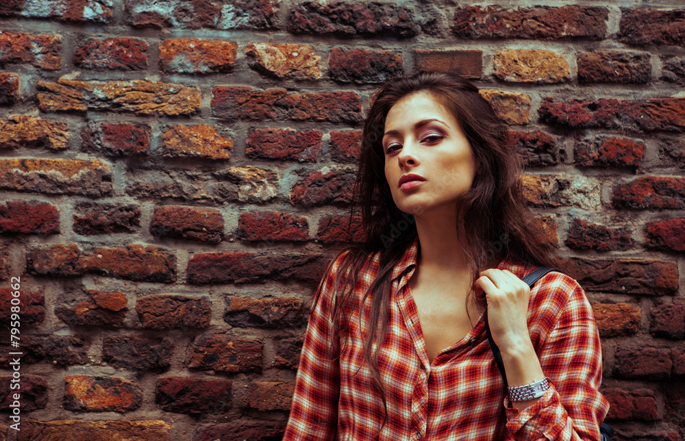 Beautiful brunette woman enjoying and standing on the old red brick wall building background in casual red shirt on the spring city. Closeup vintage banner portrait Beautiful brunette woman enjoying and standing on the old red brick wall building background in casual red shirt on the spring city. Closeup vintage banner portrait