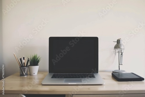 A MacBook Pro with a blank screen, reflecting the user's face and surroundings, placed on a minimalist desk against a white wall.