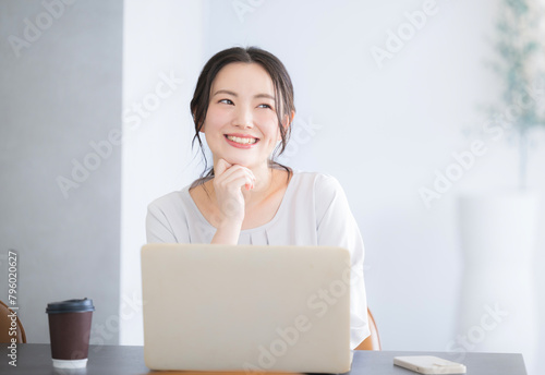 パソコンをしながら考える顎に手を当てるかわいい若い日本人(アジア人）女性