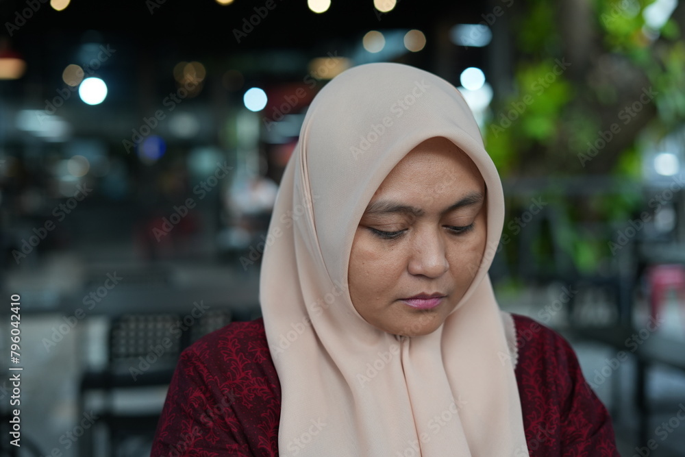 Asian woman in hijab is sitting in a cafe Asian woman in hijab is sitting in a cafe