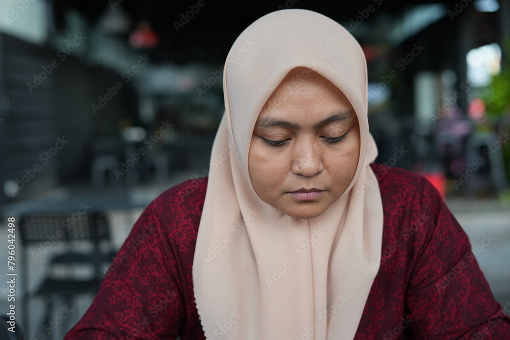 Asian woman in hijab is sitting in a cafe Asian woman in hijab is sitting in a cafe