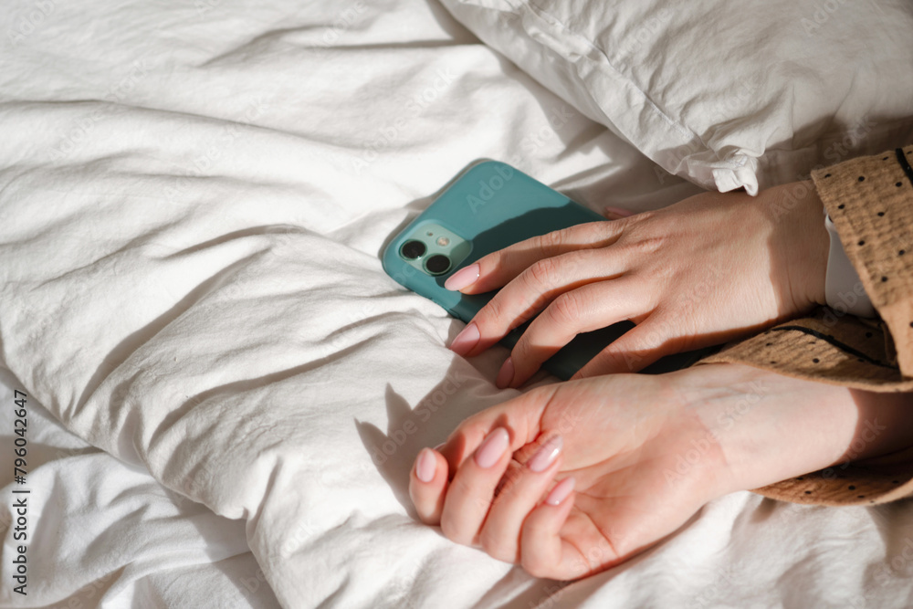 Hand holding smartphone on bed