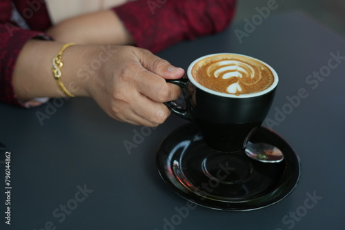 Woman's hand holding a cup of latte coffee