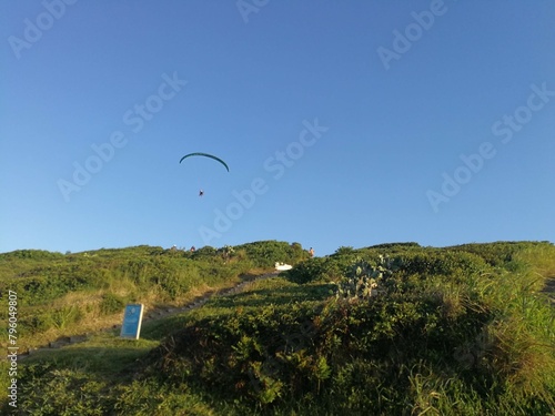 Pessoa voando de paraglider no Morro das Furnas, em Torres, Rio Grande do Sul, Brasil