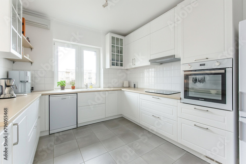 White kitchen cabinets in a Scandinavian style with modern appliances, white walls and grey floor tiles, a clean and minimalist interior design of a home or apartment in the style of modern Scandinav