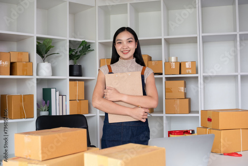 Confident small SME business owner stands holding a clipboard with inventory and shipping information in his home office. Small entrepreneurs prepare to deliver to customers. © wichayada