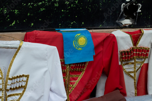 Closeup of blue flag of Kazakhstan, red and white national folk festive Georgian male costume chokha, circassian with containers for gunpowder gazyr. Bandolier. Concept of fashion, authenticity, dress photo