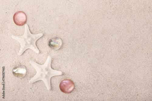 Border with star fish and red pebbles on white sand.