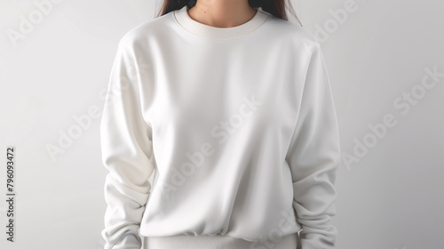 Mockup of clothes worn by a model. Close up of full upper body part from hip to neck on plain background. A woman wearing a basic white sweater on a plain light grey background. photo
