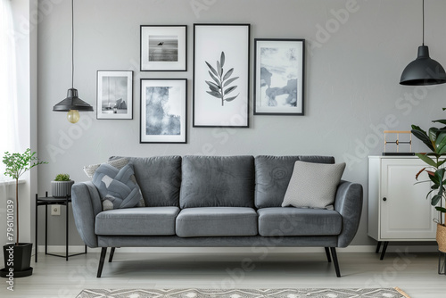 Grey settee near white cupboard in minimal living room interior with posters on the wall. copy space photo