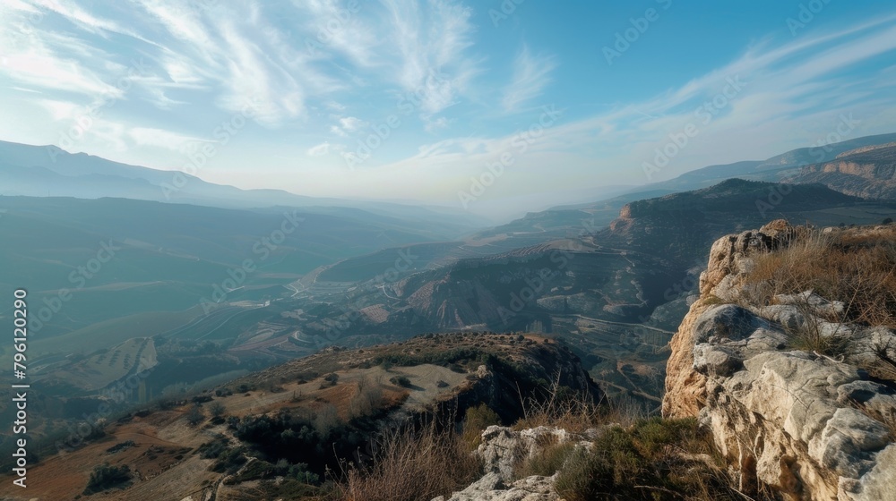 The image shows a panoramic view of mountains captured from a high vantage point. The rugged peaks and valleys create a striking landscape under the vast sky.