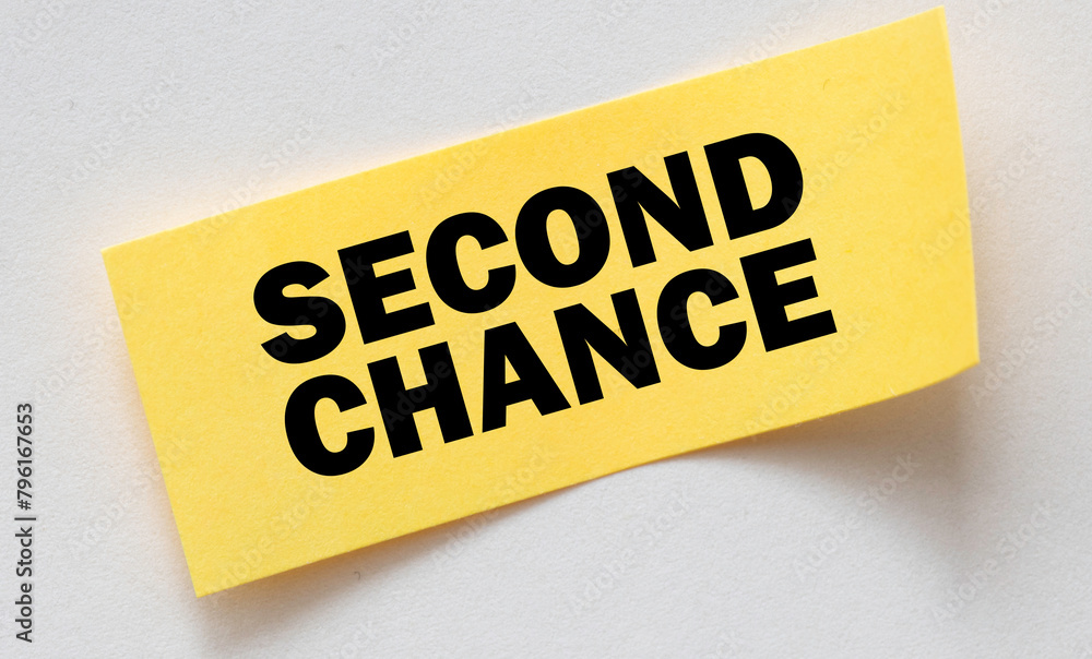 SECOND CHANCE words on a small yellow sheet of paper laid on a notebook. SECOND CHANCE words on a small yellow sheet of paper laid on a notebook.