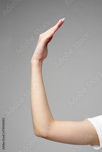 Female hand gesturing sign against gray background