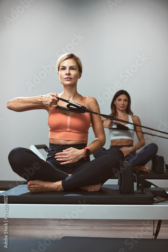 Young women exercising in a gym on pilates machines.