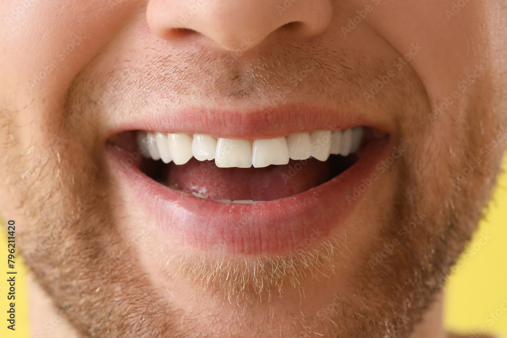 Fototapeta premium Young man smiling on yellow background, closeup