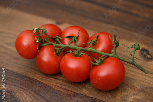 Piękne czerwone dojrzałe pomidory na gałązce na drewnianej desce 