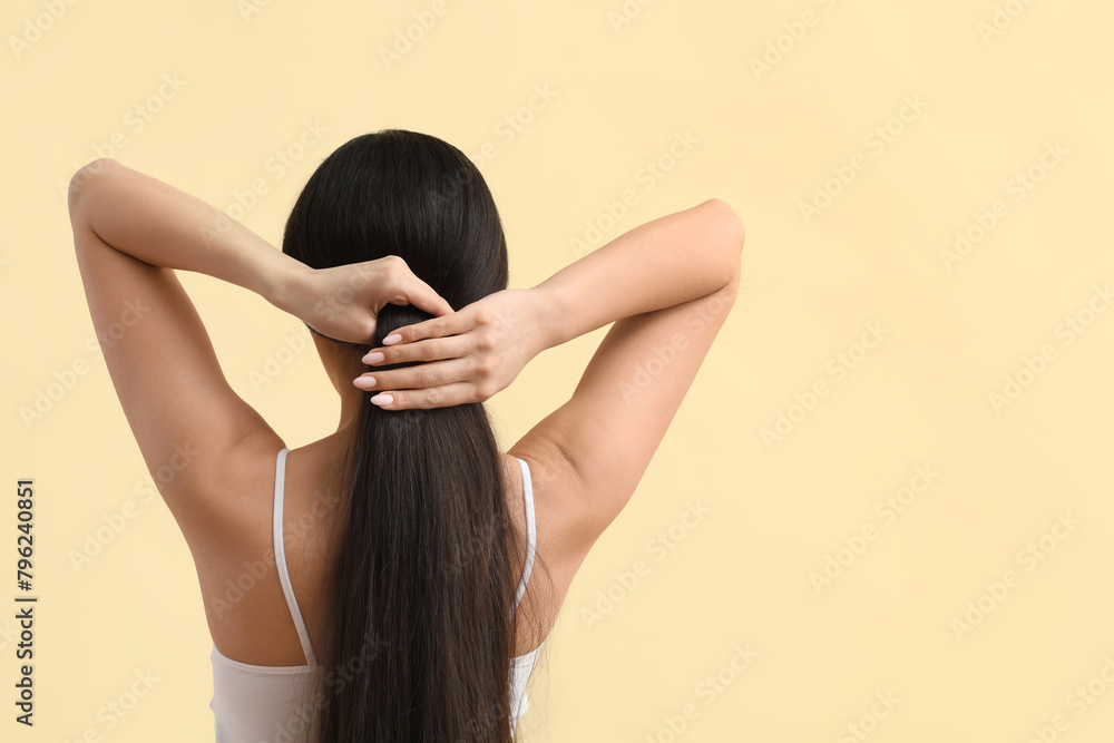 Beautiful young woman with healthy long hair on beige background, back view Beautiful young woman with healthy long hair on beige background, back view