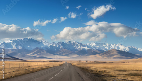 asphalt road on the prairie goes beyond the horizon to the high mountains