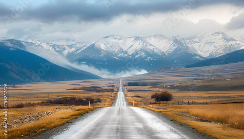 asphalt road on the prairie goes beyond the horizon to the high mountains