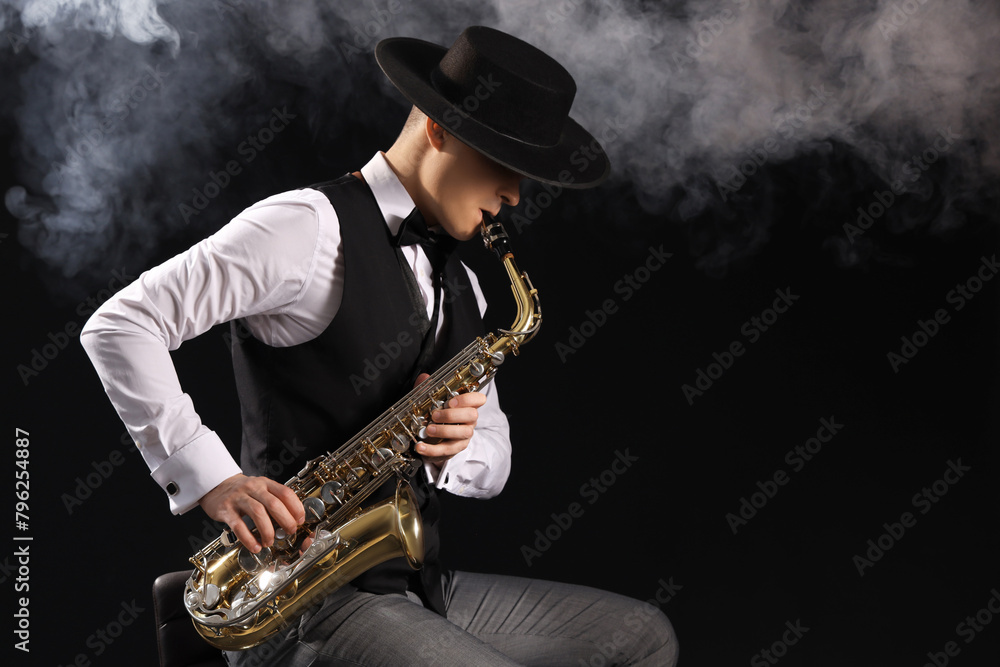 Naklejka premium Male artist playing saxophone and smoke on black background
